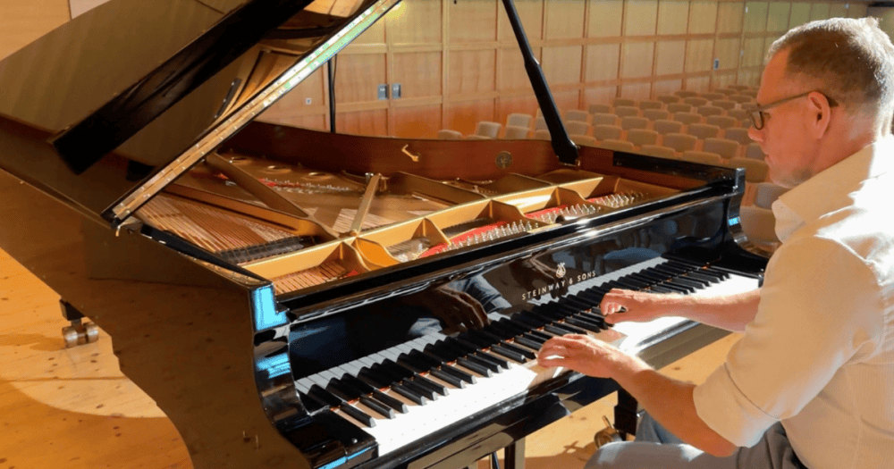 Concert technician Pascal Monti playing a Steinway & Sons grand piano with its lid open, revealing the strings and soundboard, at the Schubertiade 2026.